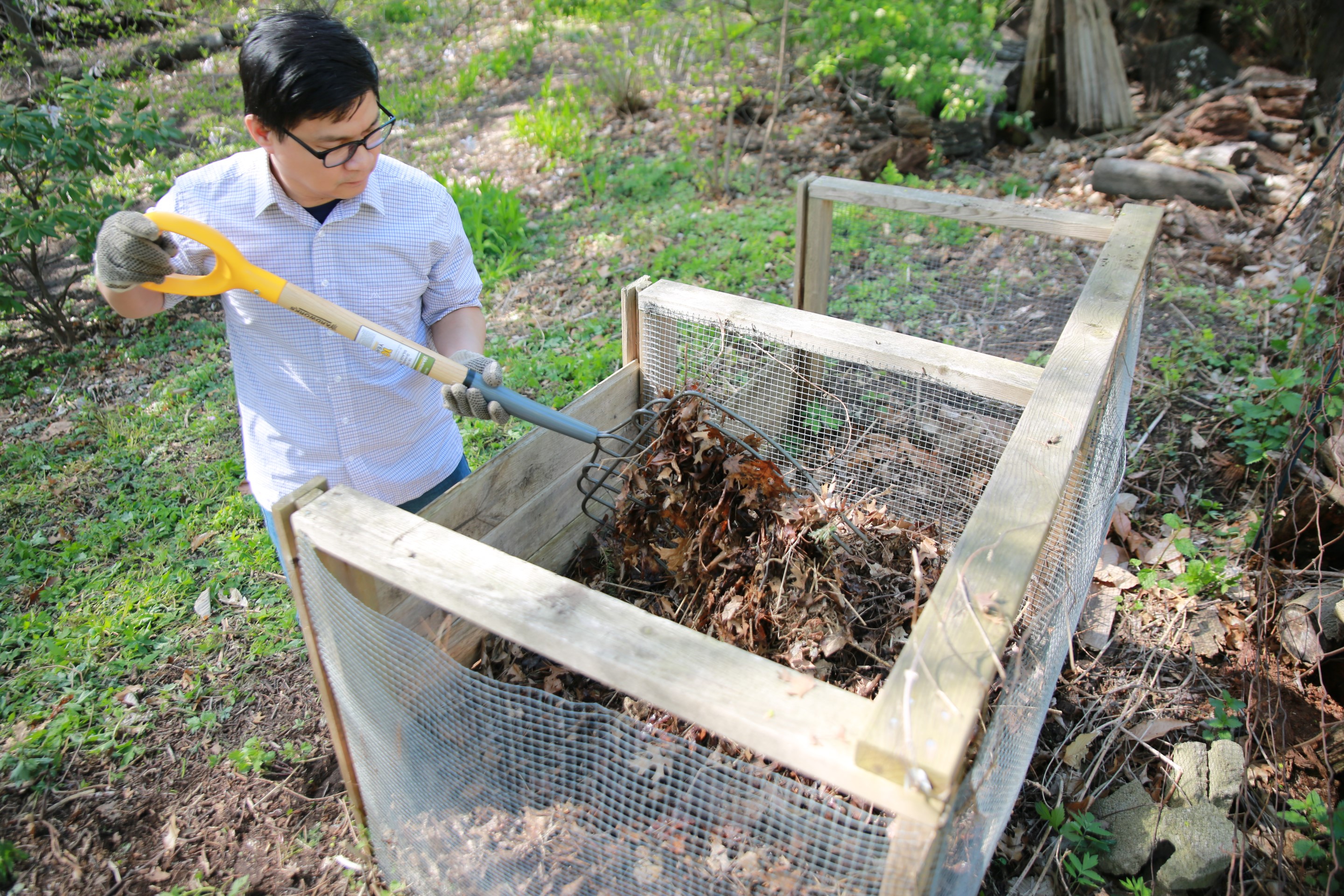 A person turning a compost pile with a pitchfork
