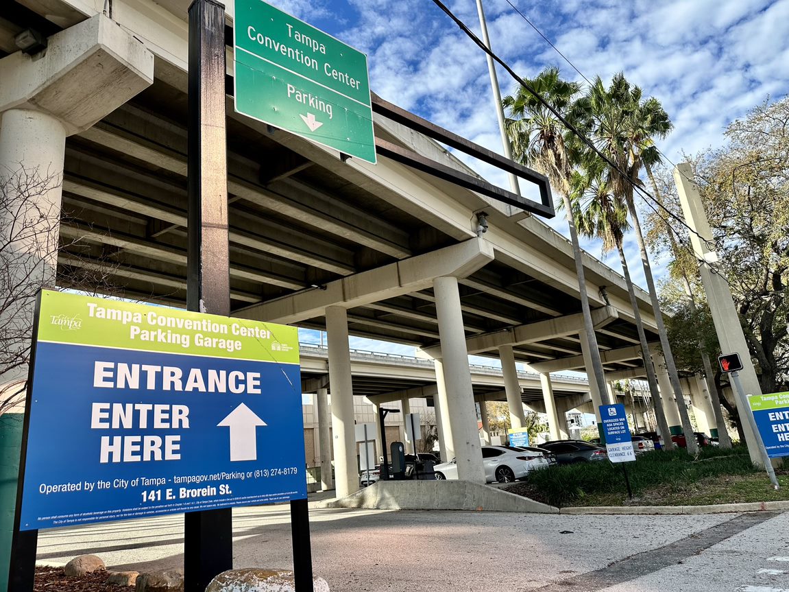 Sign reads entrance enter here with arrow pointing to Tampa Convention Center parking garage with overpass above it.