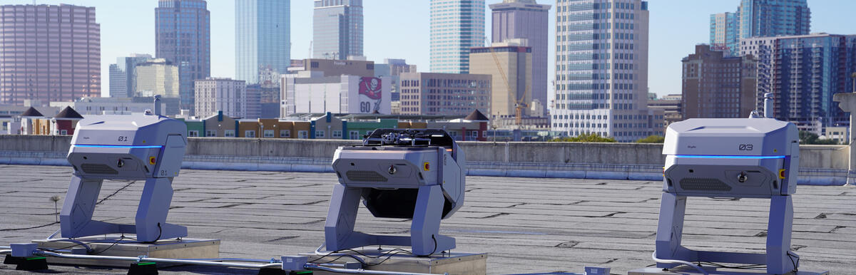 Drones on a rooftop with city skyline in the background.