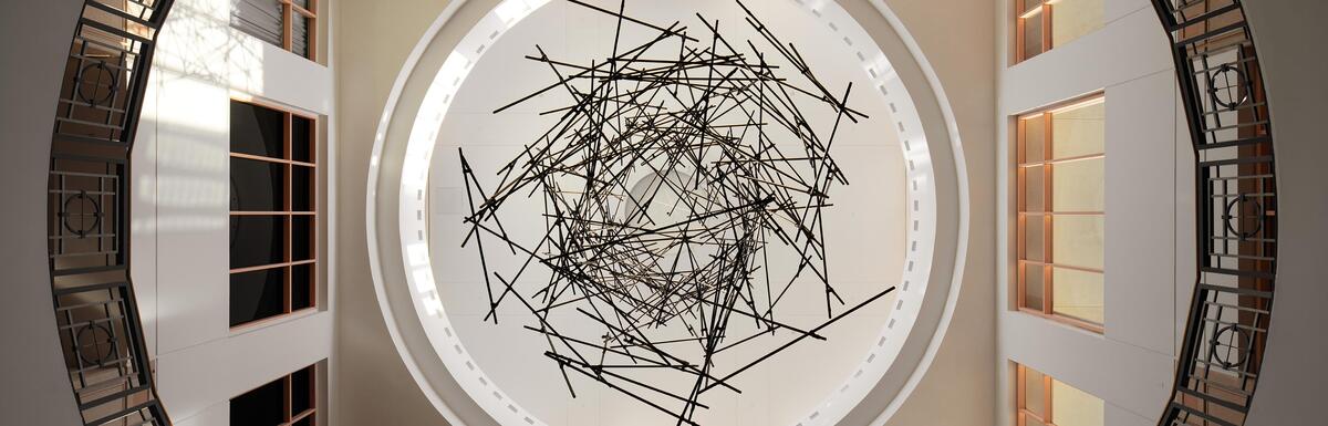 Circular skylight with metal rods resembling lightning, viewed from below inside a building atrium.