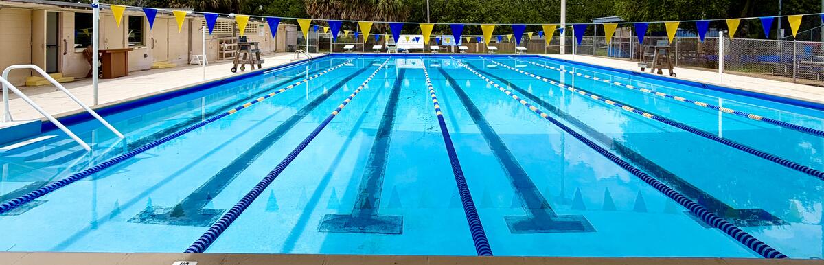 Outdoor swimming pool with lane markers, blue water, and depth marking "3 FT 6 IN" on the edge.