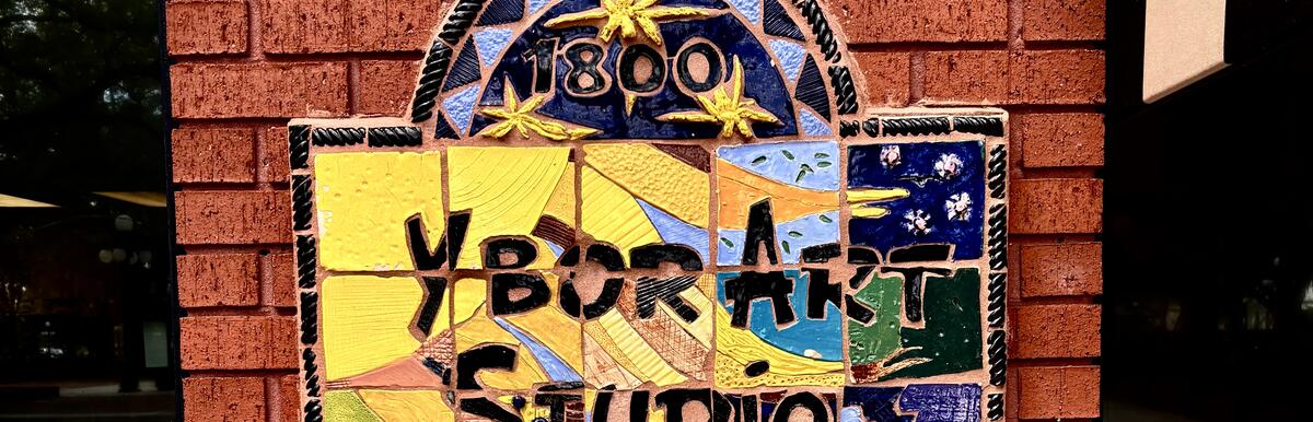 Colorful mosaic sign reading "Ybor Art Studio" on a brick wall, with "1800" above.