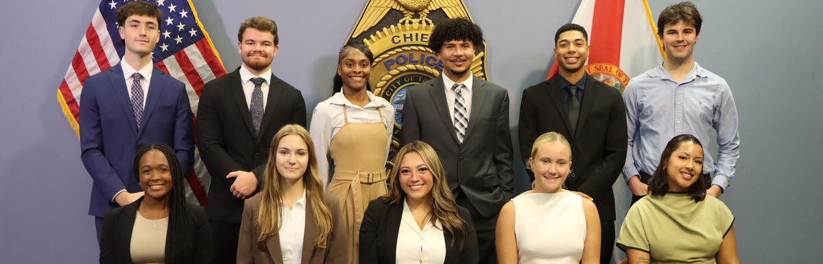 Group photo of twelve people in business attire, with U.S. and Florida flags in the background.
