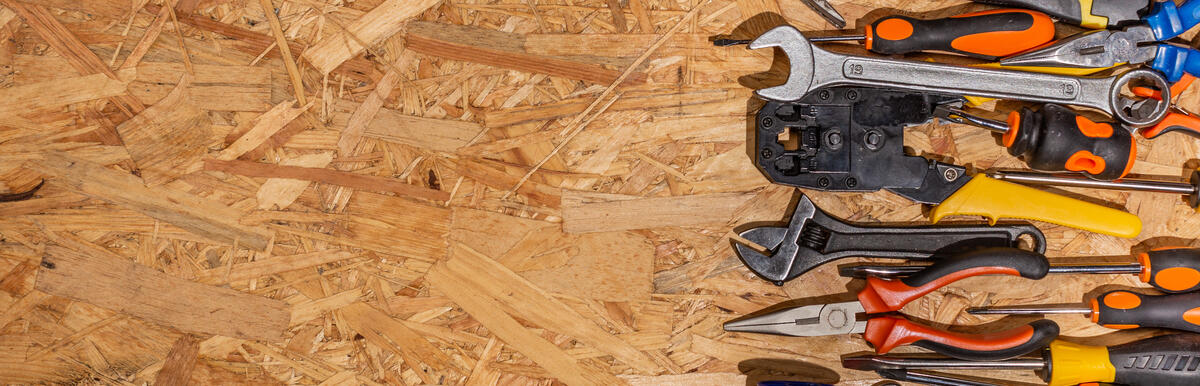 Assorted hand tools arranged on a wooden surface, with workspace on the left.