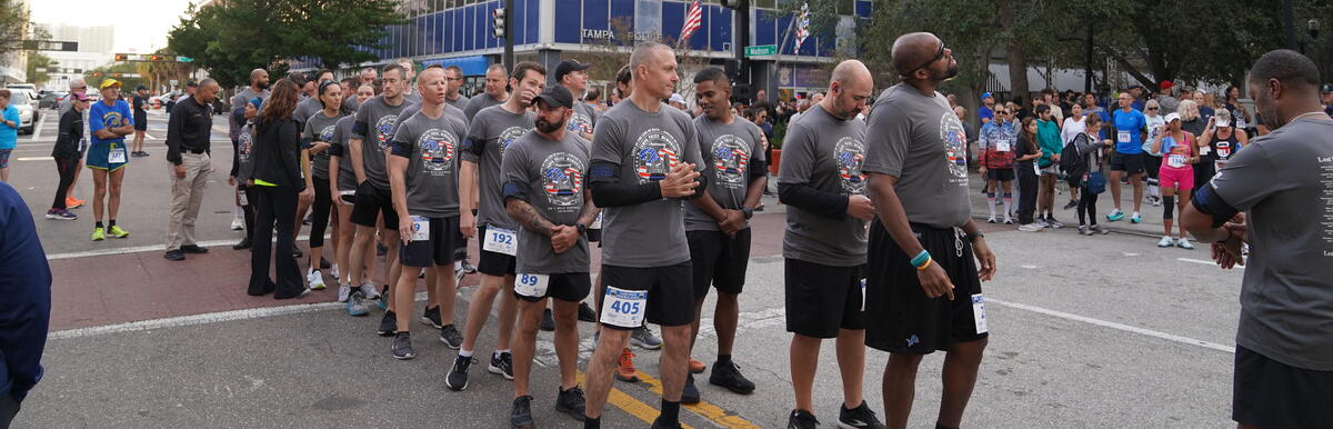 People in matching gray shirts standing in a city street, possibly a group or team event.