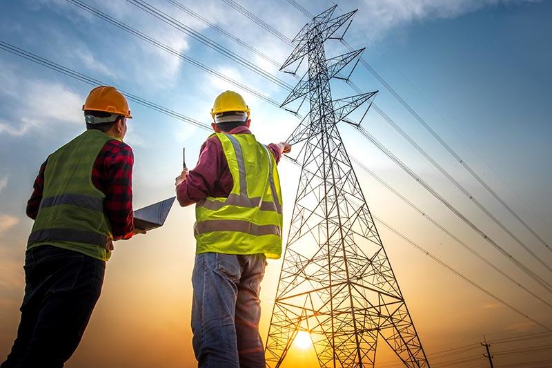 Contractors looking in the sky at an electrical tower