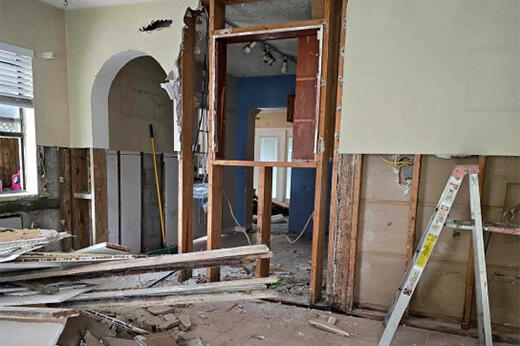 Renovation in progress; exposed beams and drywall with construction materials on the floor.