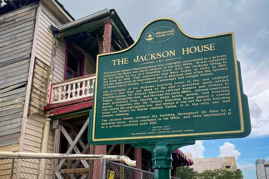 Historic marker for The Jackson House with text, near an old wooden building.