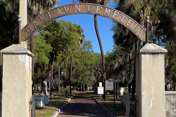 Oaklawn Cemetery entrance with trees and pathway visible.