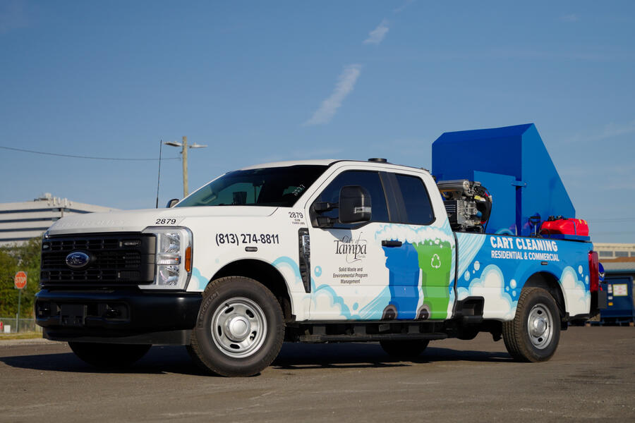 Utility truck with colorful graphics on sunny day in an urban parking lot.