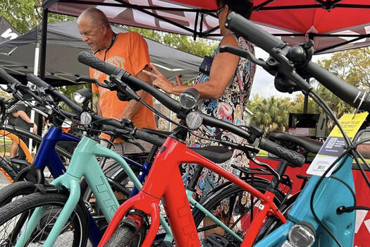 Colorful bicycles displayed at an outdoor market under red canopies.