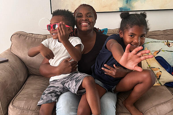 Smiling family on a couch; two children and an adult sharing a joyful moment.