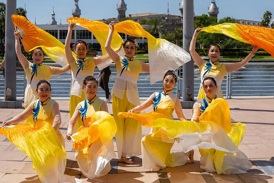 Dancers in colorful costumes perform by Tampa's riverside.