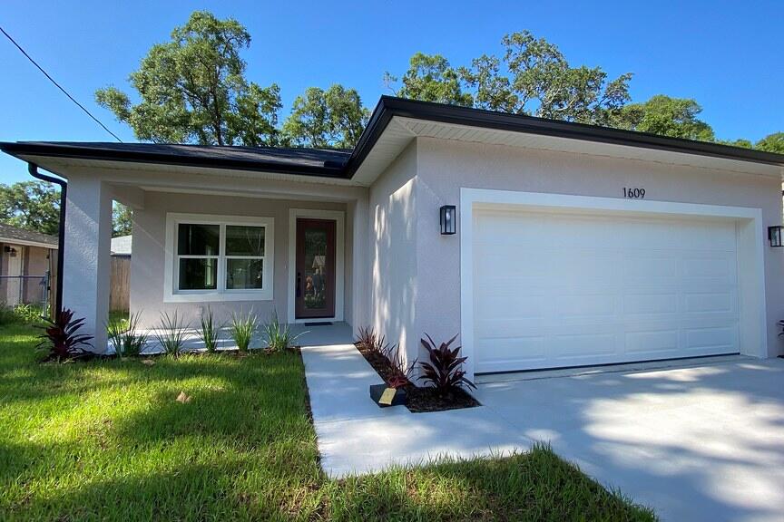 Single-story white house with a garage and manicured lawn under a blue sky.