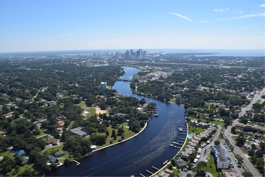 Aerial view of Tampa's green tree canopy and Hillsborough River with downtown Tampa in the distance