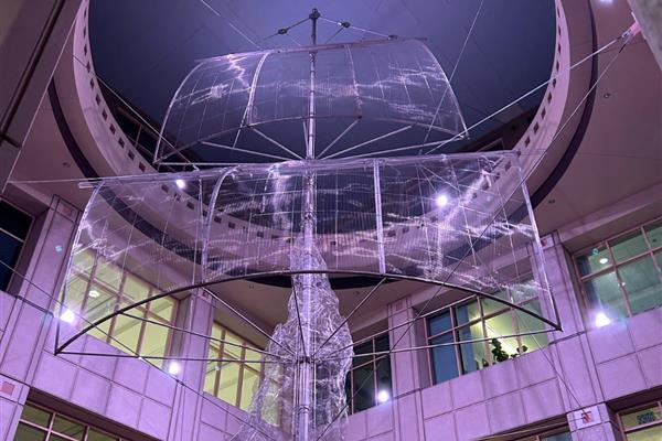 Large sculpture of a pirate ship and smoke suspended in a purple-lit atrium.