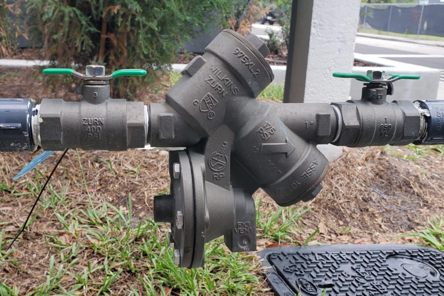 Vertical backflow prevention device installed on outdoor water pipes.