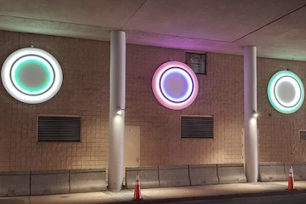 Three illuminated circles with glowing colored rings on a wall at night, unity-themed street art.