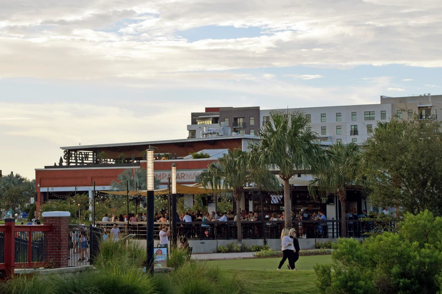 Modern commercial development with restaurants, outdoor seating, and landscaping.