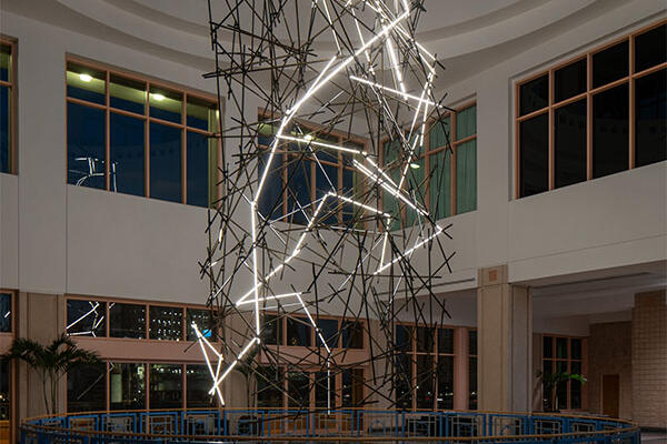 Sculpture of illuminated lightning bolt shapes suspended in a building atrium. Photo by Seamus Payne