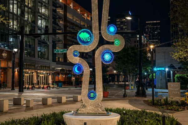 Modern sculpture with glowing blue and green circles in downtown Tampa at night.