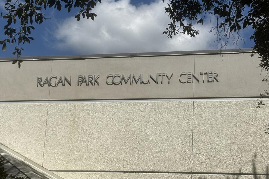 Ragan Park Community Center building exterior under a blue sky with clouds and tree branches.