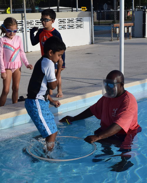 Instructor in water with student jumping into hoop