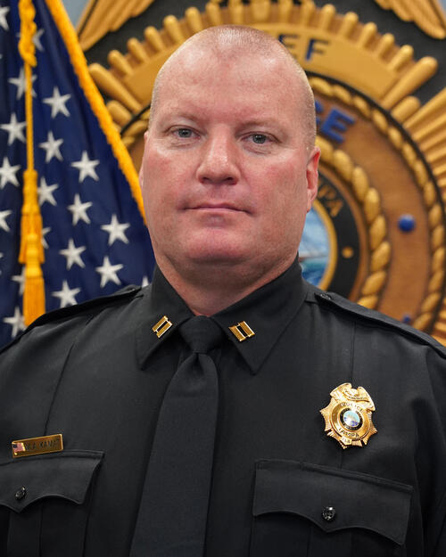 Captain Kamat in uniform in front of a police emblem and American flag.