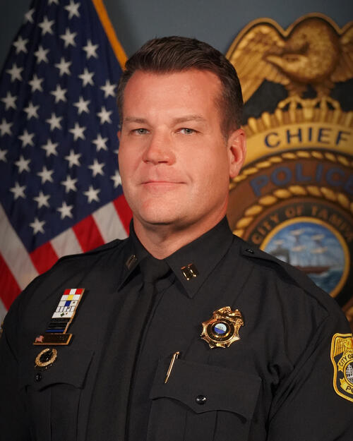 Captain Hathcox in police uniform, with badge and American flag backdrop.