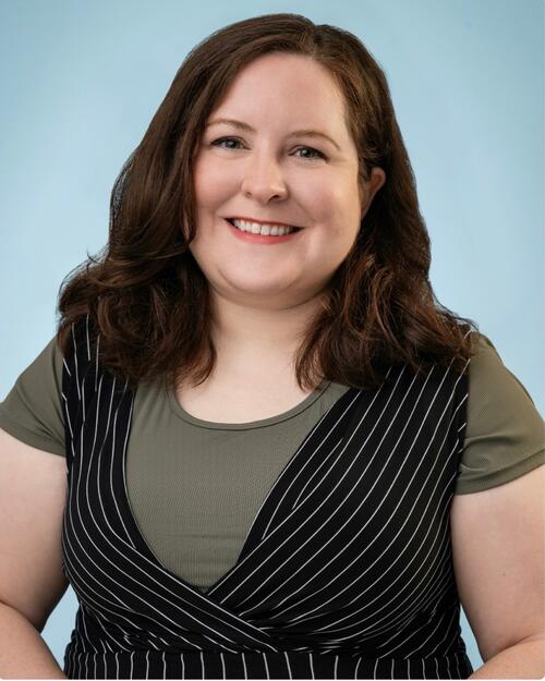 Professional portrait of Bernadette Ricard smiling against a light blue background.