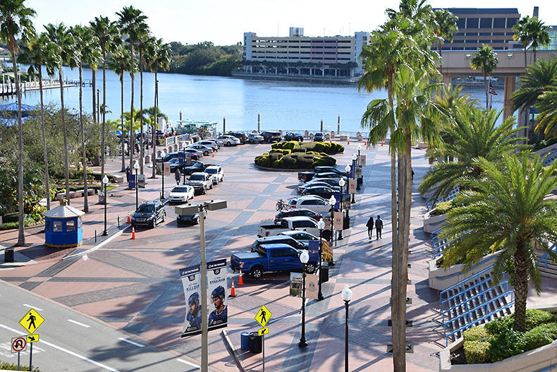 Front drive showing parked cars and palm trees in front of the waterfront