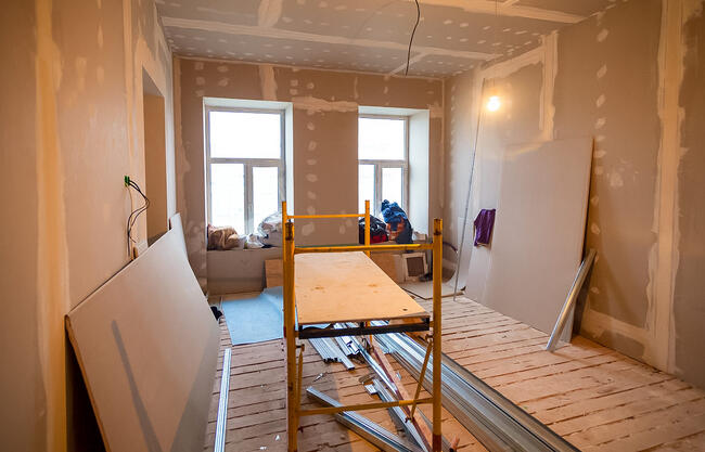 Room under renovation with scaffolding, drywall, and tools.