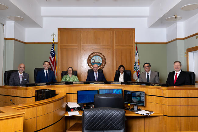 Council members seated around a conference table in council chambers.