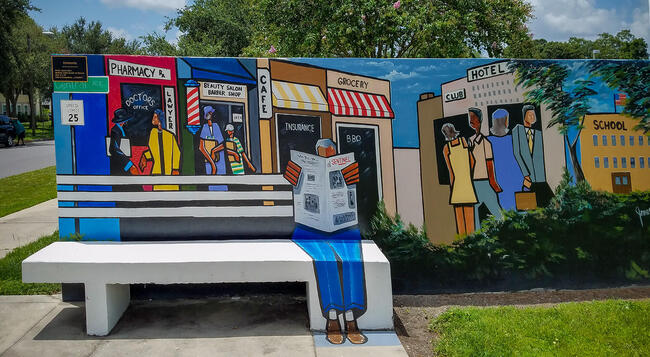Vann depicts the heart of Central Avenue's business district, where Black-owned establishments like pharmacies, beauty salons, groceries and insurance offices formed the economic backbone of East Tampa's community.
