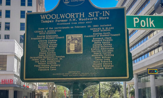 &quot;Woolworth Sit-In historic marker in front of buildings, listing participants and event details.&quot;