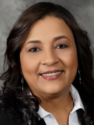 Smiling woman with dark hair, wearing a black blazer and white shirt.