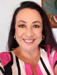 Smiling woman with dark hair, wearing a pink and black striped top.