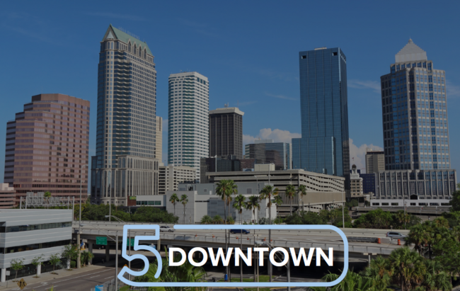 Tall skyscrapers under a clear blue sky with "5 Downtown" text overlay.