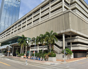 Street view of a multi-level parking garage with palm trees nearby.