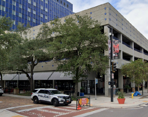 Urban street corner with a multi-story car park and police vehicle.