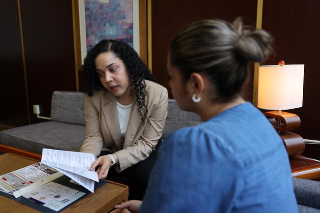 Two women discussing documents in a modern office setting.