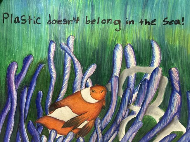Clownfish among coral, text reads: "Plastic doesn't belong in the sea!"