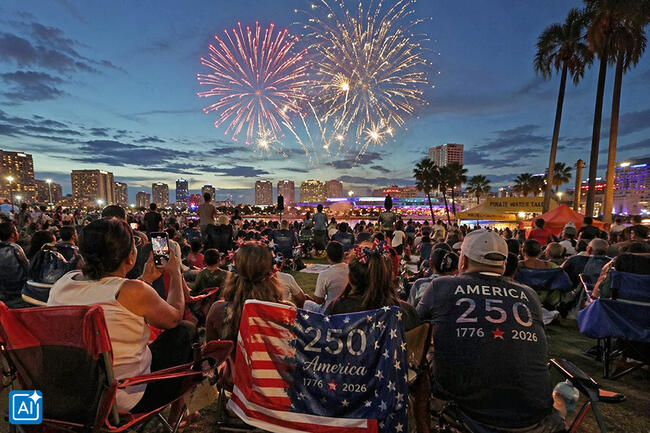 Crowd watching fireworks in city park during evening celebration.