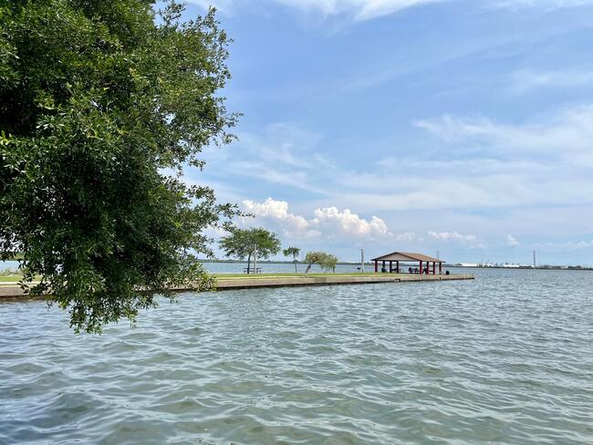 Coastal view of Palmetto Beach, with a pavilion and calm waters under a blue sky.