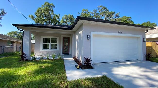 Modern suburban house with a garage and manicured lawn under a clear blue sky.