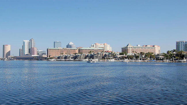 Coastal city skyline with buildings and calm water, related to sea level rise resiliency.