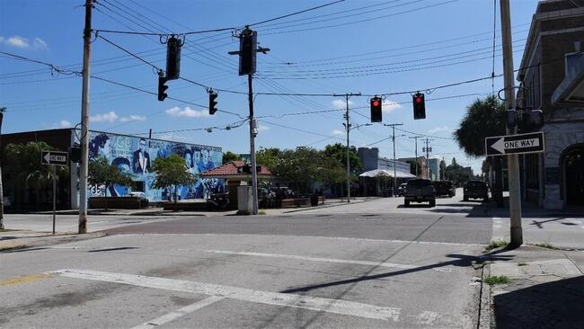 Main street in a neighborhood commercial district with traffic lights and murals.