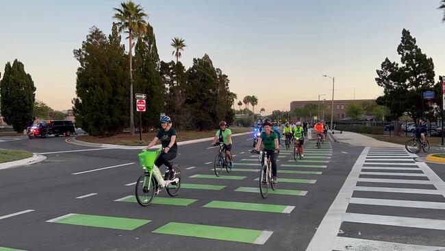 Cyclists on a green-marked lane in a transit-oriented development area.