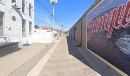 Narrow alleyway in West Tampa with mural and power lines.