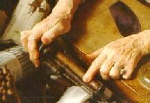 Hands rolling cigars on a wooden workbench with tobacco leaves nearby.